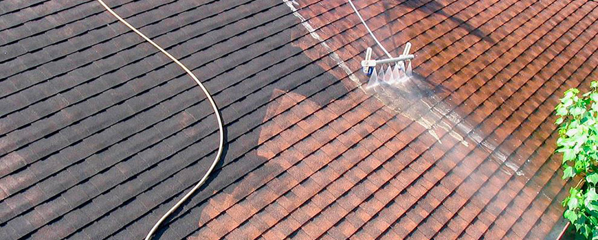 Couvreur entrain de nettoyer une toiture dans le Val d'Oise